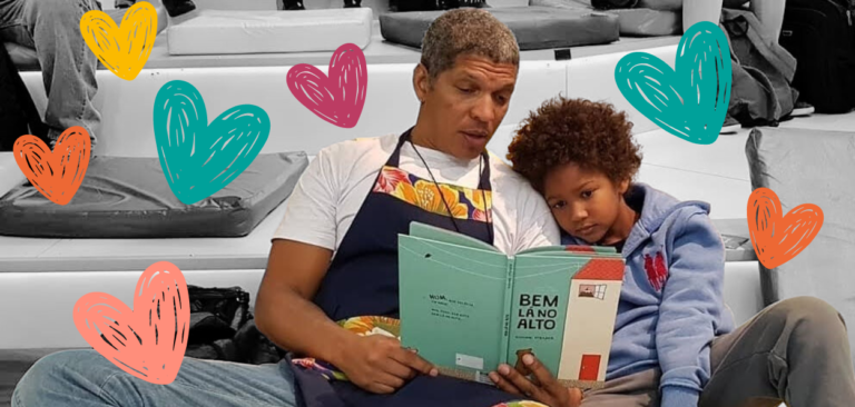 Homem negro com seu filho segurando um livro e sorrindo