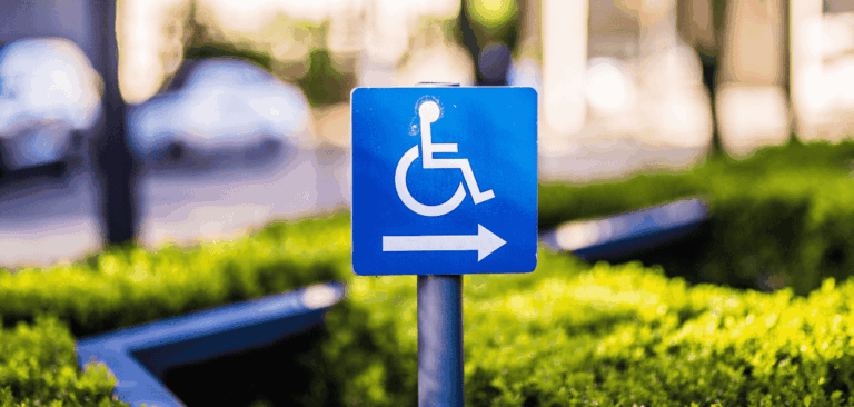 Placa azul de acessibilidade com símbolo de cadeira de rodas e seta para a direita, representando inclusão e mobilidade no espaço urbano.