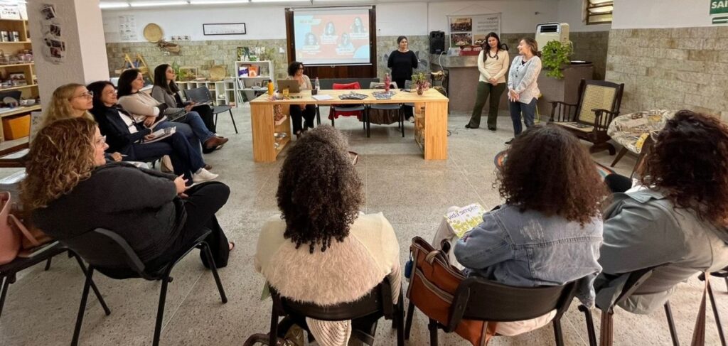 Roda de conversa com mulheres em espaço acolhedor, refletindo práticas de educação transformadora e escuta ativa.